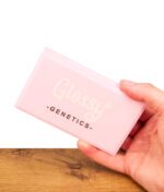 Eine Hand hält die geschlossene Glossy Genetics Digitalwaage 0,01-500g Feinwaage; auf dem rosa Klappdeckel prangt der weiße Schriftzug „Glossy -GENETICS-“.