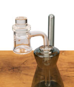 Der MJ Arsenal Sidewinder Banger mit aufgesetzter Carb Cap, einsatzbereit montiert auf einer rauchgrauen Mini-Dab-Rig mit NS10-Schliff.