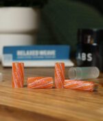RipTip Honeysuckle Glasfilter Lifestyle – orange-weiße Glasfilter verschiedener Durchmesser auf Holztisch mit Rolling Papers