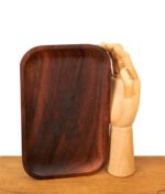 Hochkantes RAW Wooden Rolling Tray Mixing Tray aus Holz. Dunkel gemaserte Drehunterlage neben einer hölzernen Gliederhand zum Größenvergleich.