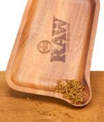 Detailansicht des RAW Rolling Tray aus Holz. Zerkleinerte Kräuter sammeln sich in der geschwungenen Ecke der Drehunterlage als Einfüllhilfe.