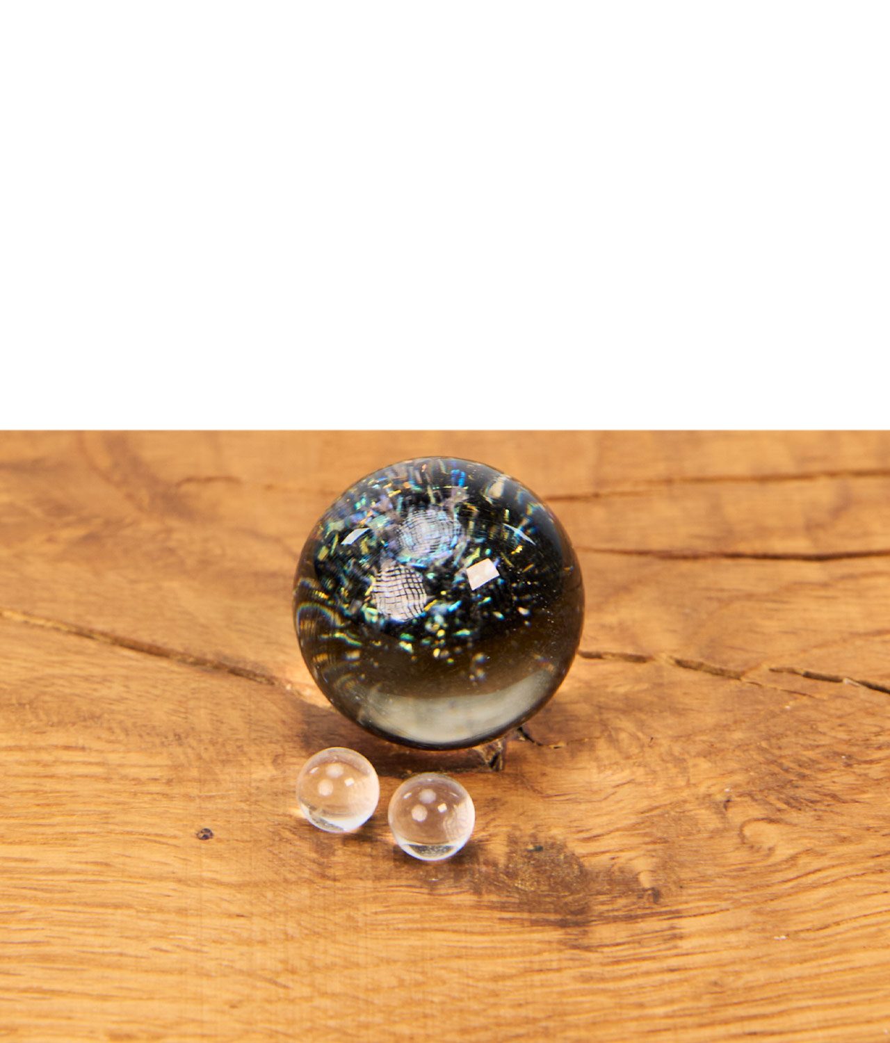 mj-arsenal-blender-marble-kit-galaxy-jpg MJ Arsenal Terp Blender Murmel Kit in der Farbe Galaxy mit gemusterter Glas-Marble und zwei klaren Terp Pearls auf einem Holztisch.