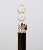 Schimmernder Puffco Pivot Bubble Top Iridescent aus Glas. Der kugelförmige Aufsatz ist passgenau auf den schwarzen Vaporizer aufgesteckt.