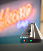 Silberner Volcano Classic steht vor "Volcano Bar" LED Schild