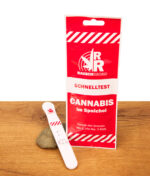 Rauschradar Cannabis Speichel-Schnelltest mit roter Verpackung und weißer Testkassette auf einem Stein und Holztisch.