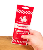 Rote Verkaufsverpackung des Rauschradar Cannabis Speichel-Schnelltests, aufrecht in einer Hand gehalten.