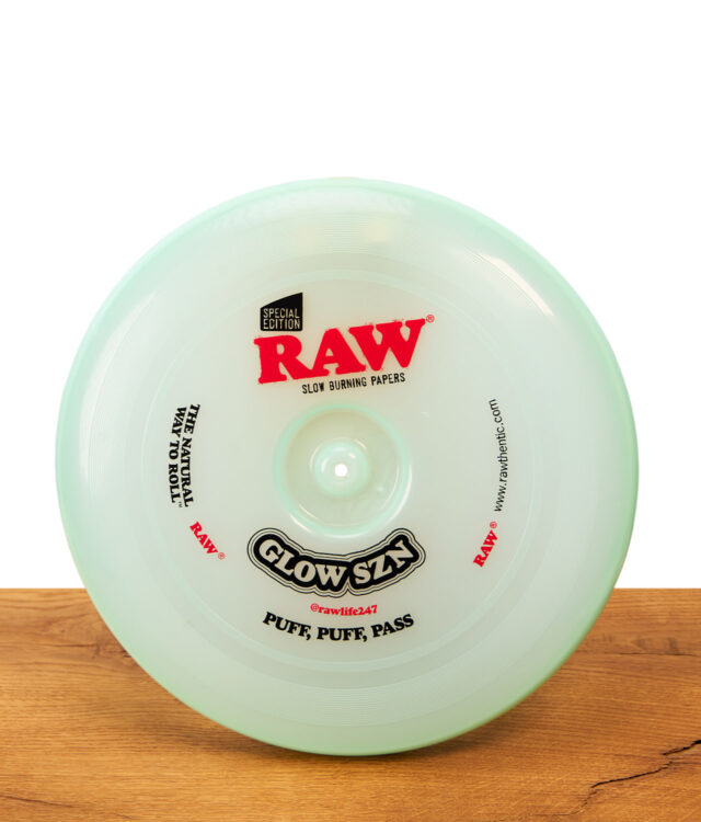 RAW Frisbee Cyan Glow SZN Special Edition: Runde, mintgrüne Kunststoff-Frisbee und Rolling Tray auf einer Holzoberfläche.