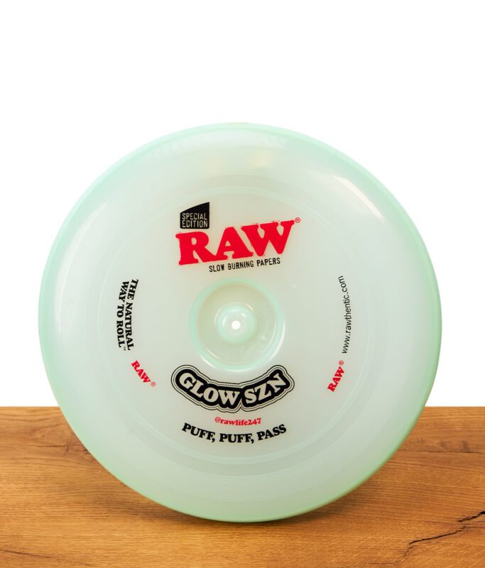 RAW Frisbee Cyan Glow SZN Special Edition: Runde, mintgrüne Kunststoff-Frisbee und Rolling Tray auf einer Holzoberfläche.