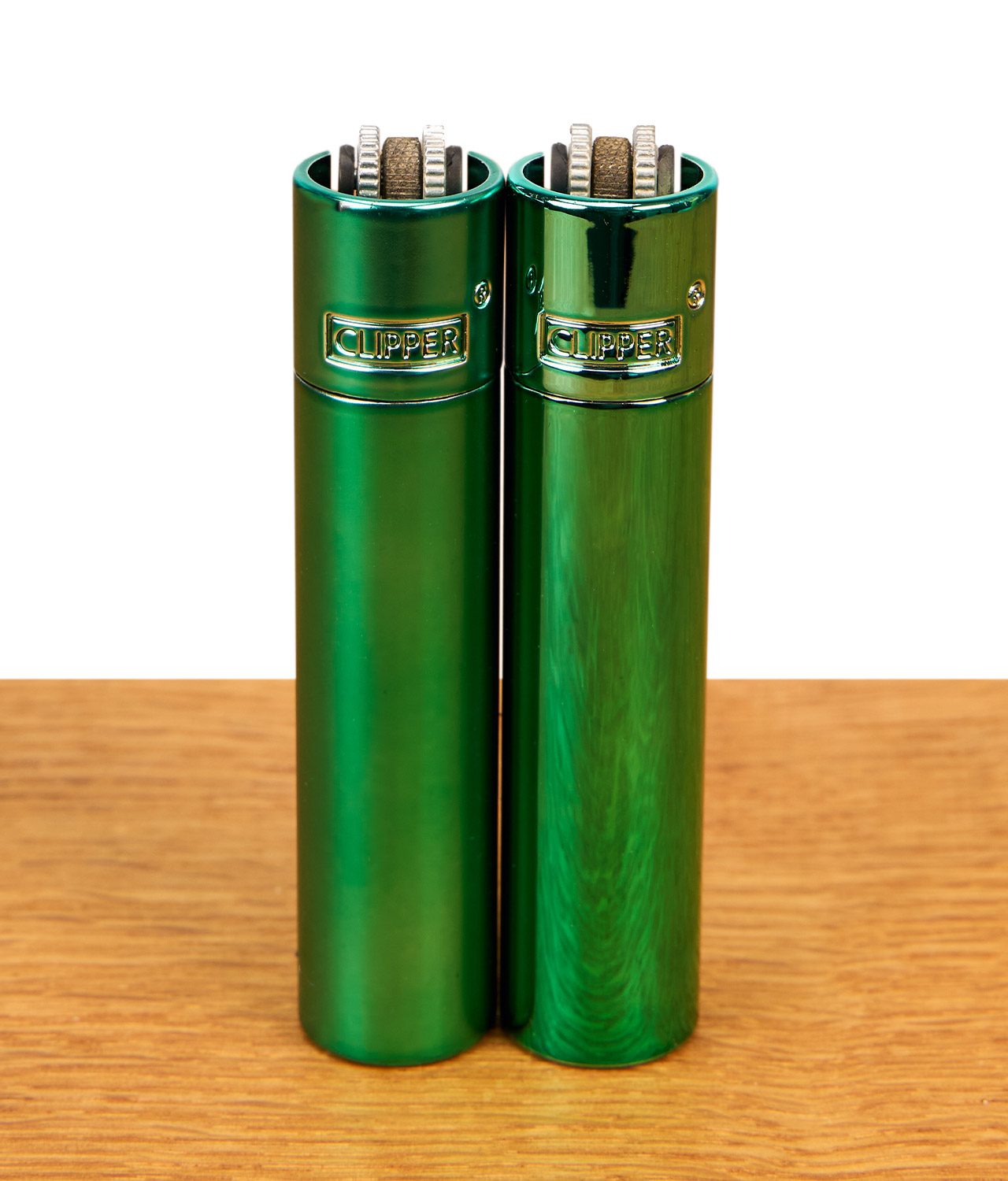 clipper-metall-turquoise-2er-serie-jpg Clipper Metall Turquoise Feuerzeuge im 2er-Set mit mattem und glänzendem Finish nebeneinander auf Holz.