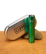 Mattes Clipper Metall Turquoise Feuerzeug stehend neben einer geprägten Metalldose und einem Stein auf Holz.