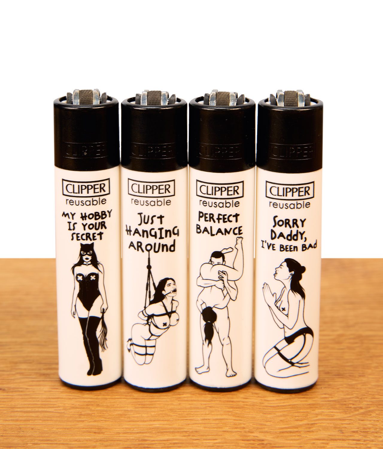 clipper-ffx-adult-6-4er-serie-jpg Clipper FFX Adult #6 Reibradfeuerzeuge im 4er-Set mit schwarz-weißen BDSM-Motiven und Sprüchen auf Holz.