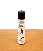 Clipper FFX Adult #6 Sorry Daddy Reibradfeuerzeug mit erotischem Motiv einer knienden Frau auf einer Holzoberfläche.