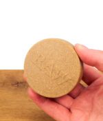 RAW Magnetic Stash Jar Dose mit geprägtem Logo und faseriger Textur, von einer Hand gehalten.