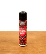 Einzelansicht des schwarzen Clipper Feuerzeugs aus der „Kiss me #3“ Kollektion mit einem Muster aus kleinen roten Herzen und dem großen, zentralen Schriftzug „FUCK YOU“.