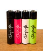 Clipper Stayhigh 4er-Set wiederbefüllbare Reibradfeuerzeuge in Schwarz, Pink, Weiß und Neongrün mit geschwungenem Schriftzug auf Holz.