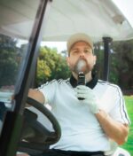 Ein Mann im Golfcart nutzt das Dr. Dabber Switch GO E-Rig und atmet eine Dampfwolke aus.