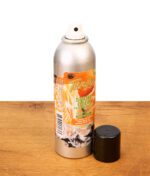 Tangie Smoke Odor Exterminator Sprühdose auf Holzoberfläche, enzym-basierter Rauch-Geruchsvernichter mit danebenliegender schwarzer Kappe.