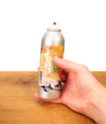 In der Hand gehaltene Tangie Smoke Odor Exterminator Sprühdose, enzym-basierter Rauch-Geruchsvernichter ohne Kappe über Holzfläche.