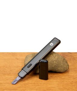 G Pen Melt Hot Knife ohne Kappe auf einem Stein platziert, elektronisches Dabbing-Werkzeug mit Bedienknopf und Keramik-Ladetipp.