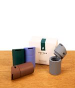 Puffco Pivot Mundstück Set in vier Farben samt Originalverpackung auf Holz dekoriert, das graue Silikonteil ist geöffnet.