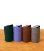 Vier Puffco Pivot Mundstücke aus mattem Silikon in den Farben Grün, Lila, Braun und Grau nebeneinander auf einem Holztisch.