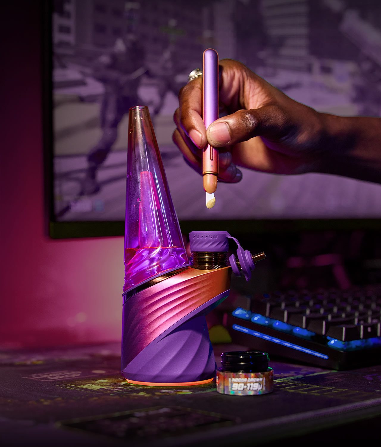 puffco-peak-pro-plasma-edition-jpg Das Peak Pro Plasma E-Rig neben einem Glasbehälter beim Laden eines Dabs per Hot Knife in passender Edition