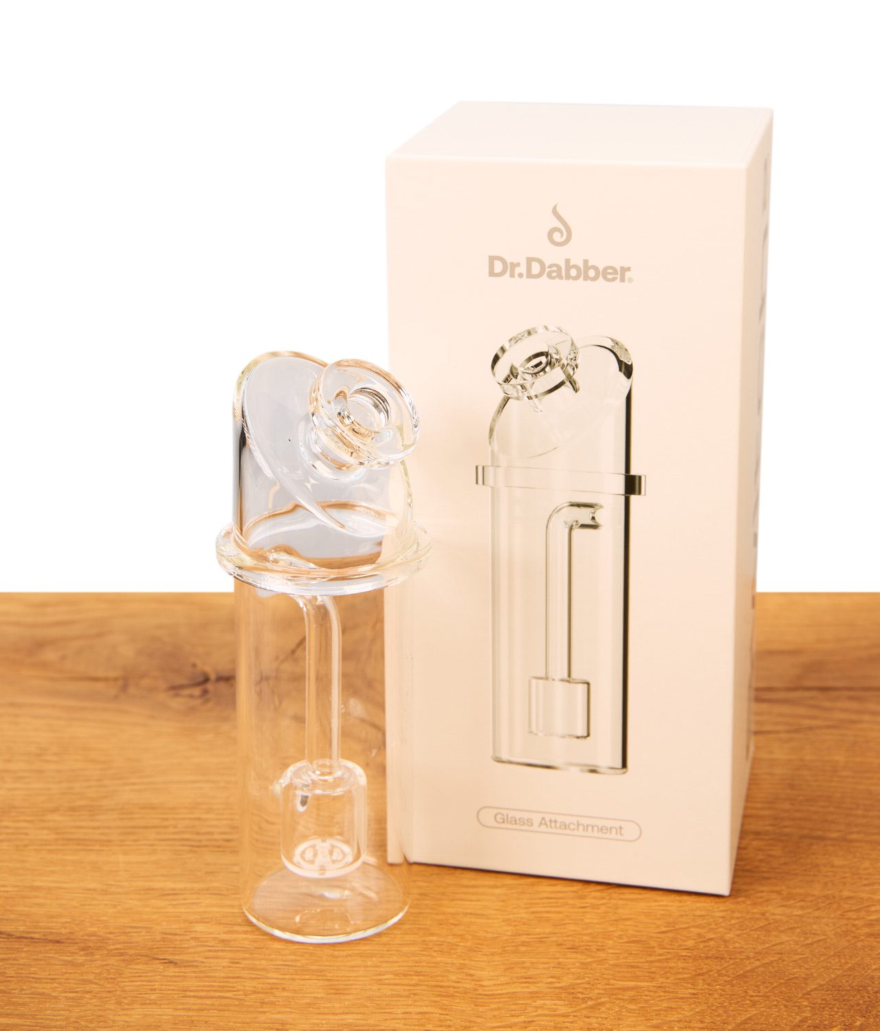 dr-dabber-switch-2-ersatzglas-3-jpg Dr. Dabber Switch 2 Ersatzglas aus Borosilikatglas neben seiner weißen Verpackung auf einer Holzoberfläche.