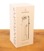 Weiße Originalverpackung des Dr. Dabber Switch 2 Ersatzglases auf einer Holzoberfläche.