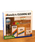Randy's Cleaning Kit in der Originalverpackung mit Sichtfenster auf einer Holzplatte, das alle Reinigungsutensilien zeigt.