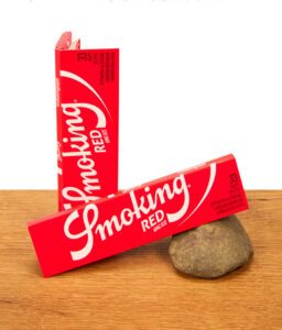 Zwei rote Packungen Smoking Red King Size Blättchen auf einer Holzoberfläche
