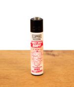 Clipper Döner Collection Dreh dich Baby auf Holz. Weißes, nachfüllbares Feuerzeug mit rotem Spieß-Motiv und Metall-Zündrad.