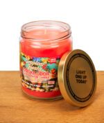 Geöffnete Smoke Odor Duftkerze Tropical Fiesta im Glas auf einem Holztisch. Der goldfarbene Metalldeckel lehnt seitlich am Gefäß.