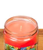 Detailansicht der Smoke Odor Duftkerze Tropical Fiesta auf Holz. Geöffnetes Glasgefäß zeigt das glatte rote Wachs und den zentrierten Docht.
