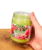 Hand hält eine Smoke Odor Exterminator Candle Watermelon Zlushie. Die offene Anti-Geruch Kerze aus Glas mit grünem Wachs.