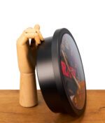 Seitenansicht der RAW Black Stash Clock, gestützt von einer Holzhand auf einem Tisch. Zeigt die unauffällige Bautiefe des Geheimverstecks.