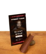 Futurola x Tyson 2.0 The Toad Blunt Wrap Verpackung auf Holz neben einem braunen, tabakfreien Wrap, der auf einem Stein liegt.