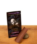 Schwarze Futurola x Tyson 2.0 Knockout OG Blunt Wrap Verpackung auf Holz, daneben ein brauner Wrap auf einem kleinen Stein.