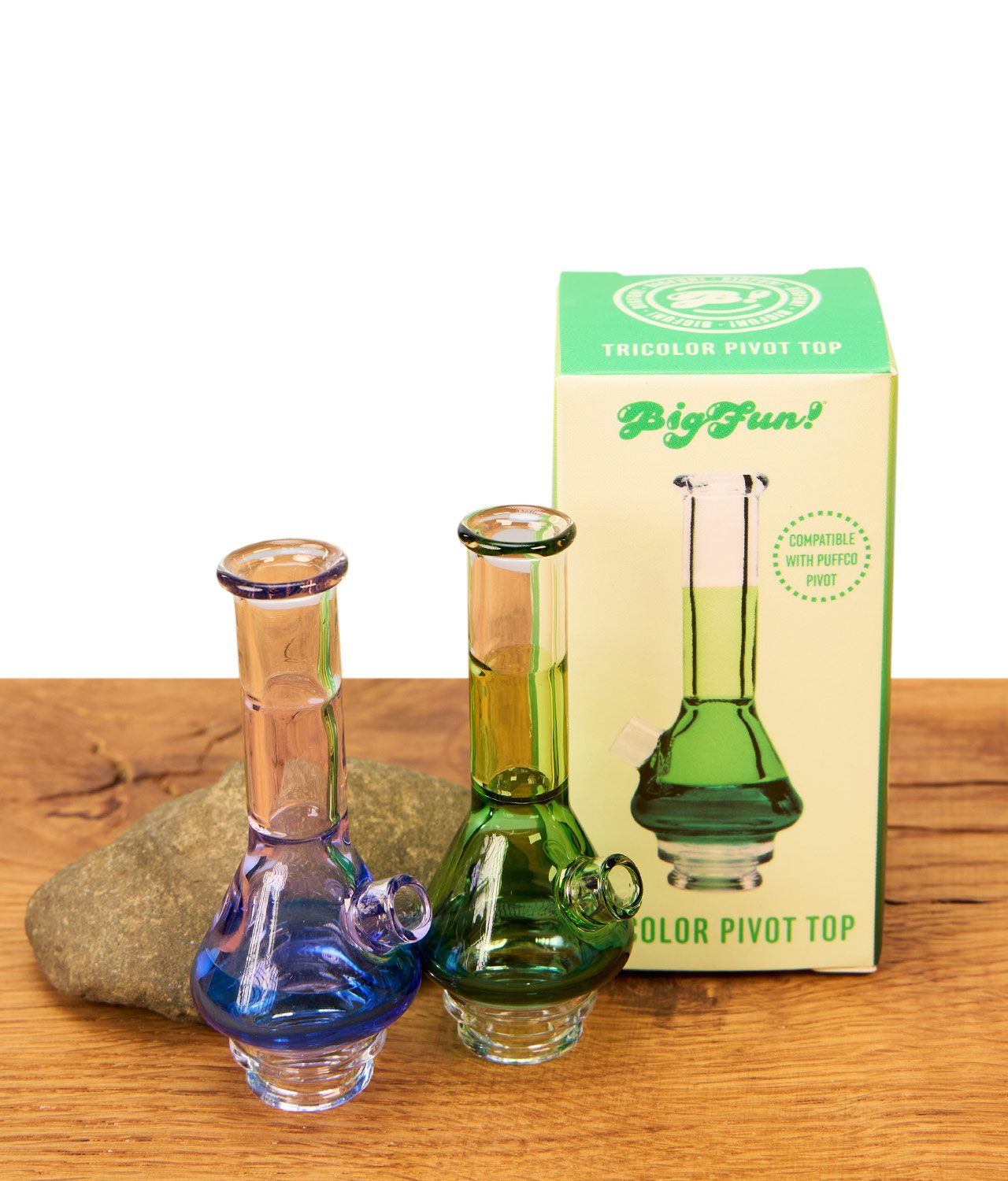 tricolor-pivot-top-1-jpg Blauer und grüner BigFun! Tricolor Pivot Top Glasaufsatz neben der grünen Originalverpackung und Stein auf Holz.