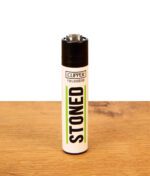 Weißes Clipper Feuerzeug Stoned mit schwarzem Schriftzug und grünen Akzenten auf Holztisch, nachfüllbares Gasfeuerzeug aus Nylon.