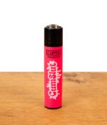 Pinkes Clipper Feuerzeug Adult Slogan CumSlut auf Holzuntergrund, nachfüllbares Nylon-Gasfeuerzeug mit Zündstein.